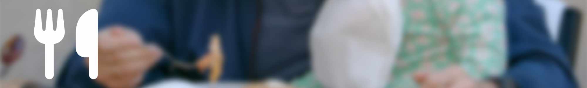 A blurred image of a man feeding a young girl who is sat on his knee overlayed with an icon of a fork and knife